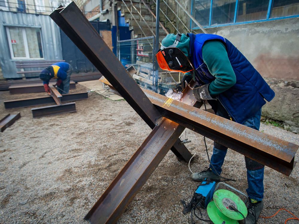 2 people in protective gear welding together steel beams