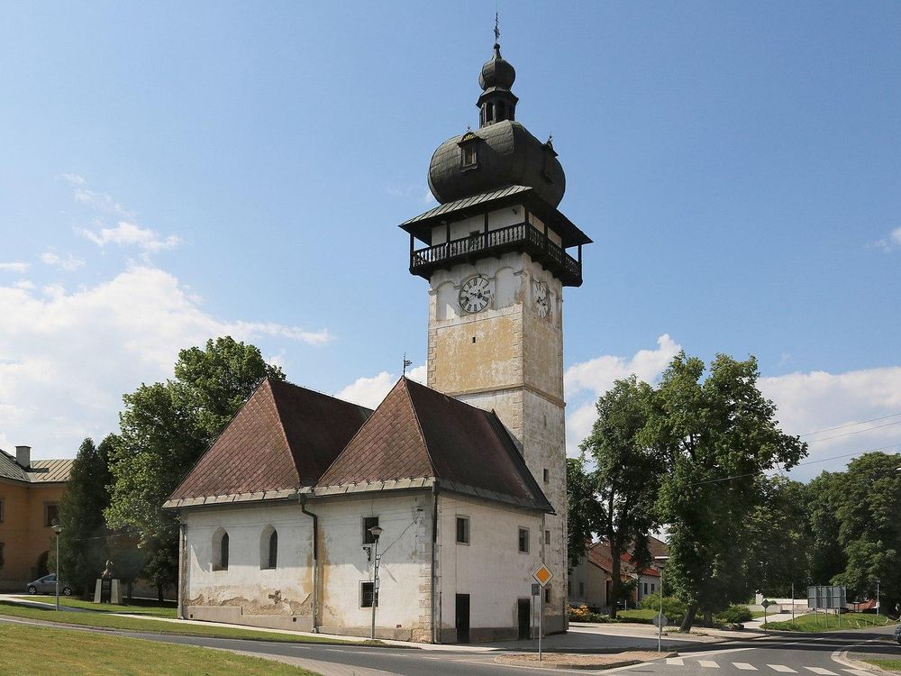 One tall tower with a domed black roof, next to two small buildings 