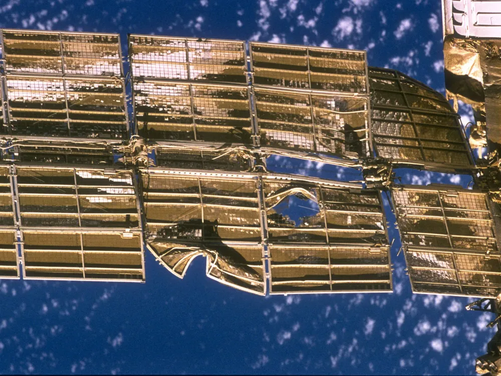 A golden solar panel on the Mir Space Station with a hole and a few tears from a collision