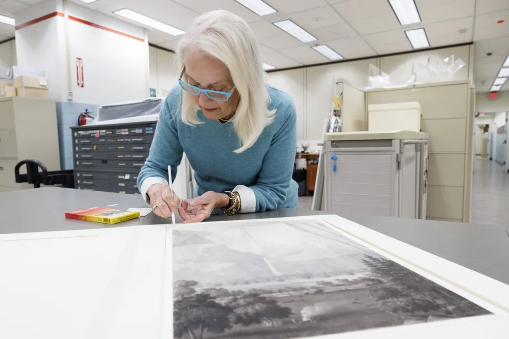 A woman in a blue sweater working on a drawing