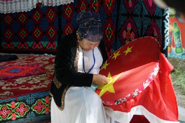 Woman sewing People's Republic stars in Kazakh Village, Western China thumbnail