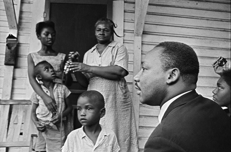 Dr. Martin Luther King Jr. , chats with African-Americans during a door-to-door campaign in 1964.