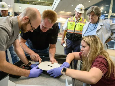 Staff remove the touchable moon rock’s mount while curator Priscilla Strain, second from right, looks on.