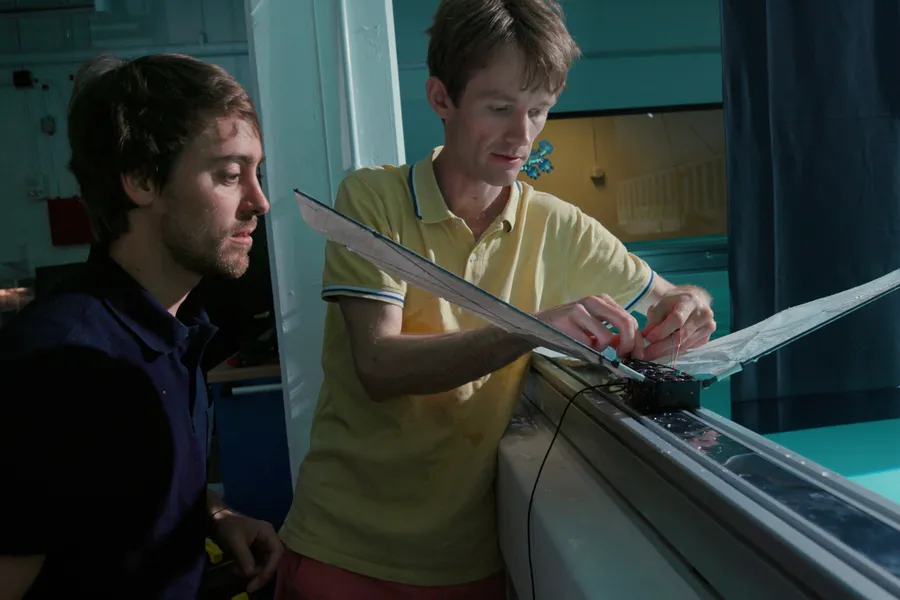 two men working on a winged robot