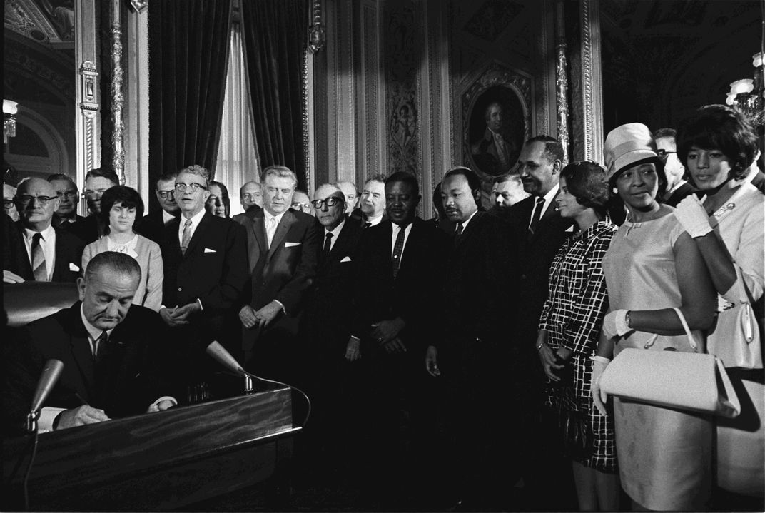 Lyndon B. Johnson signs the Voting Rights Act of 1965 in the presence of Martin Luther King Jr., Vivian Malone and other civil rights activists.