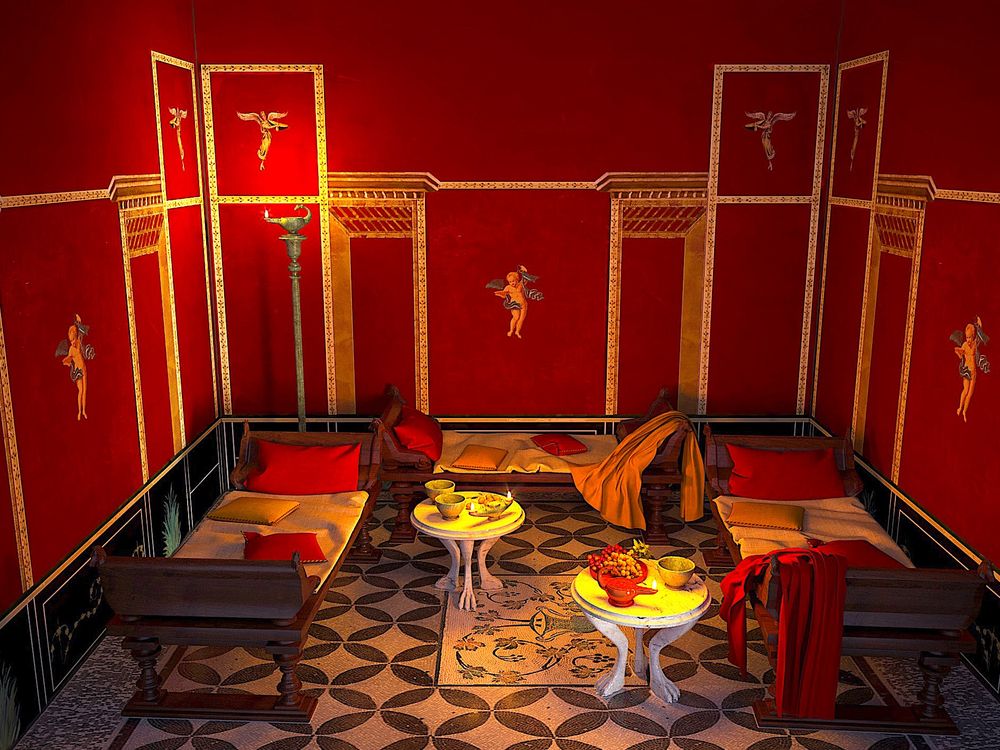 A red walled room with white and black tiled mosaic, with a large decorative piece in the center of the floor that depicts a grape vine extending from a vase and three low beds against each wall