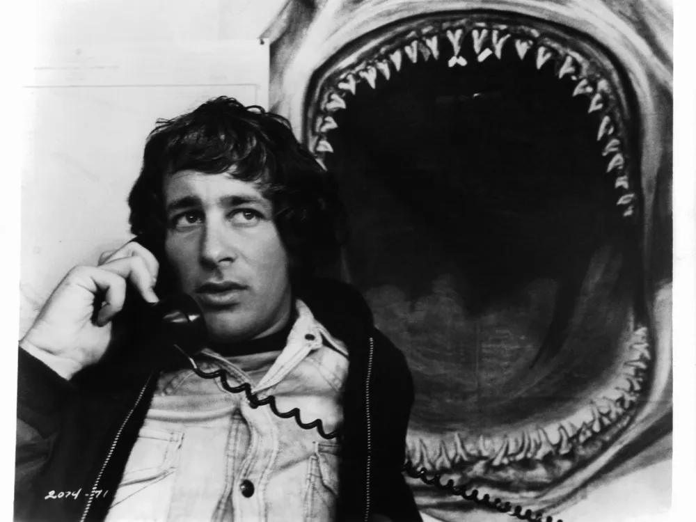 spielberg on the phone in front of a shark jaw
