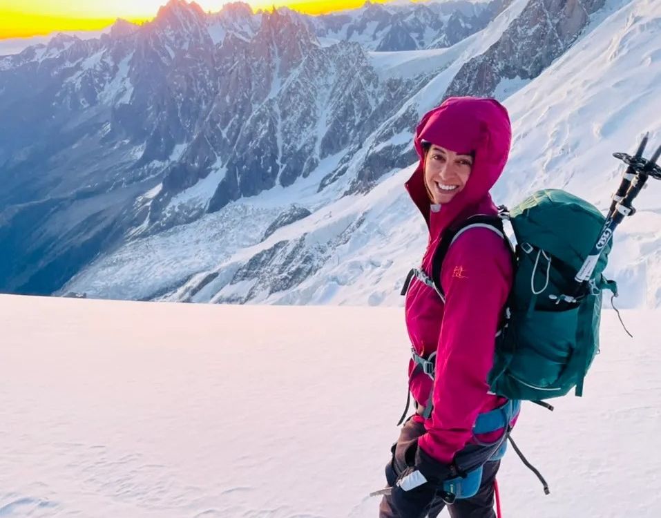 Preet smiles in front of mountains with a pack on her back