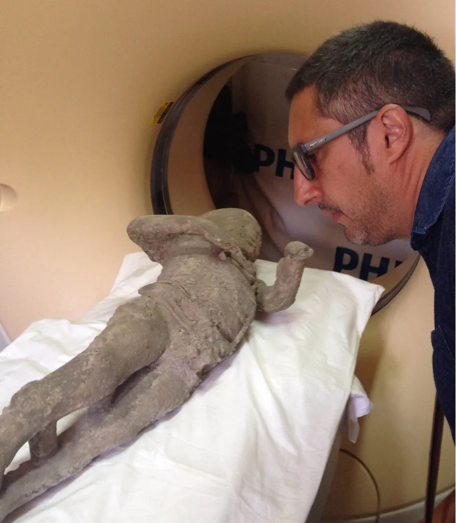 A man standing next to a plaster cast of a human body near a tunnel