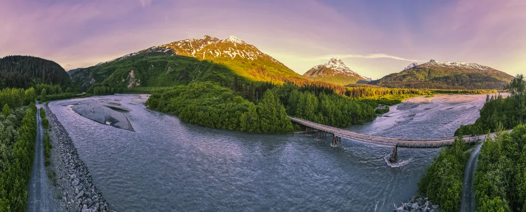 Lowe River Bridge in Valdez is surrounded by majestic mountains, swirling clouds and glacier-fed waters.