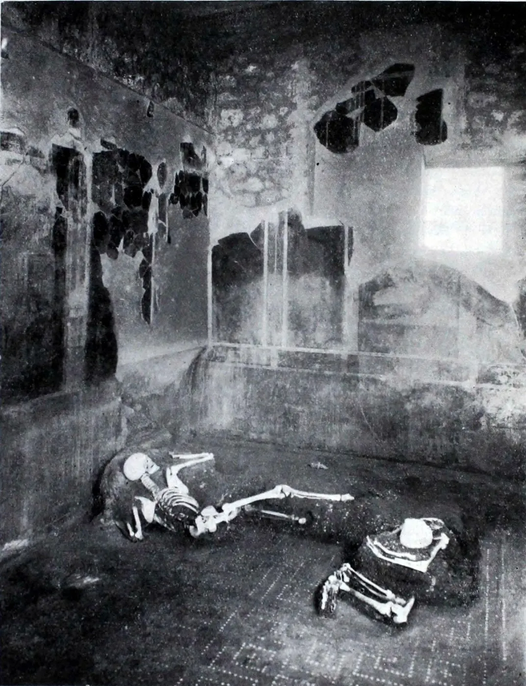 Two skeletons lie in a house in a black-and-white image