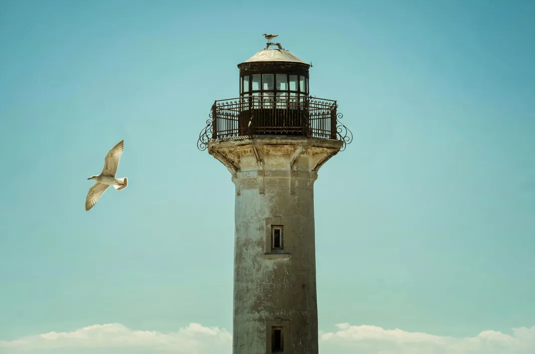 11 - Seagulls enjoy the view from the top of an old lighthouse in a small seaside village.