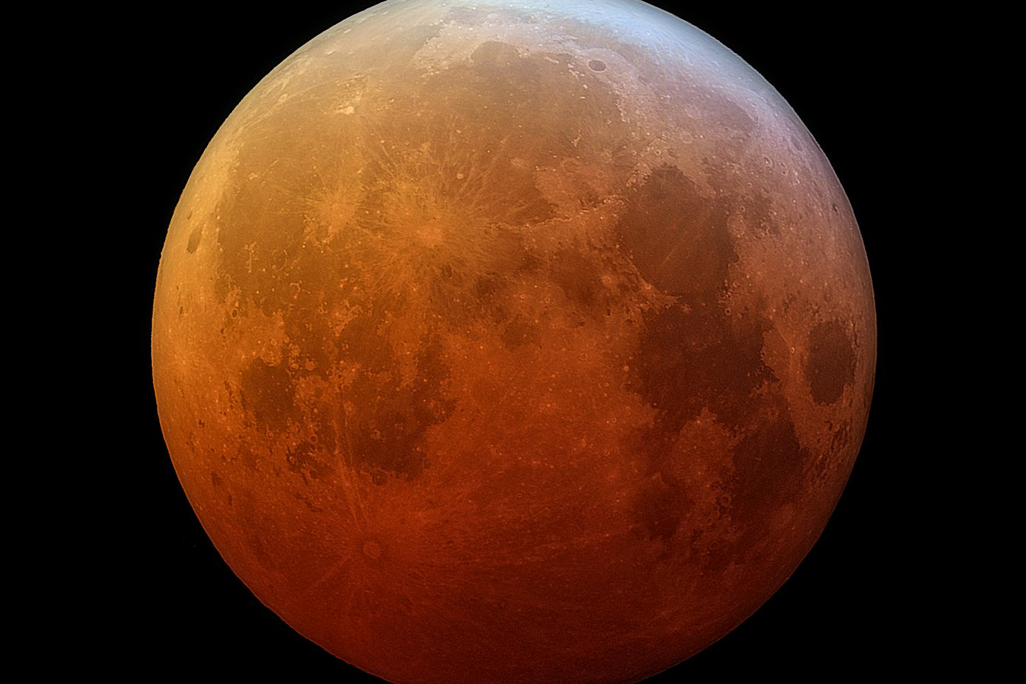 A photo of a lunar eclipse where the moon looks red-orange at the bottom which fades up to normal gray-white at the top