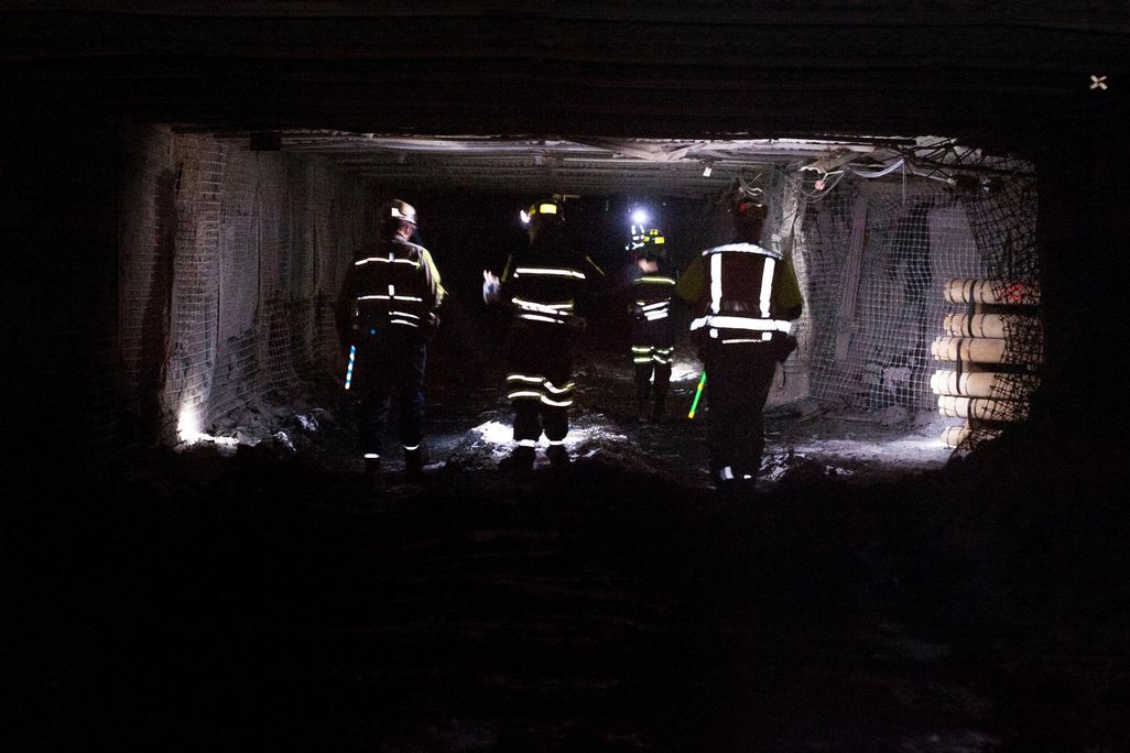Coal miners dramatically walk through a tunnel