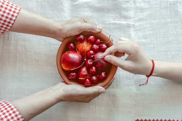 Grandmother treats granddaughter with cherries. thumbnail