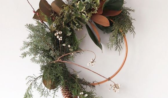 A modern evergreen wreath on a metal hoop displayed on a white background