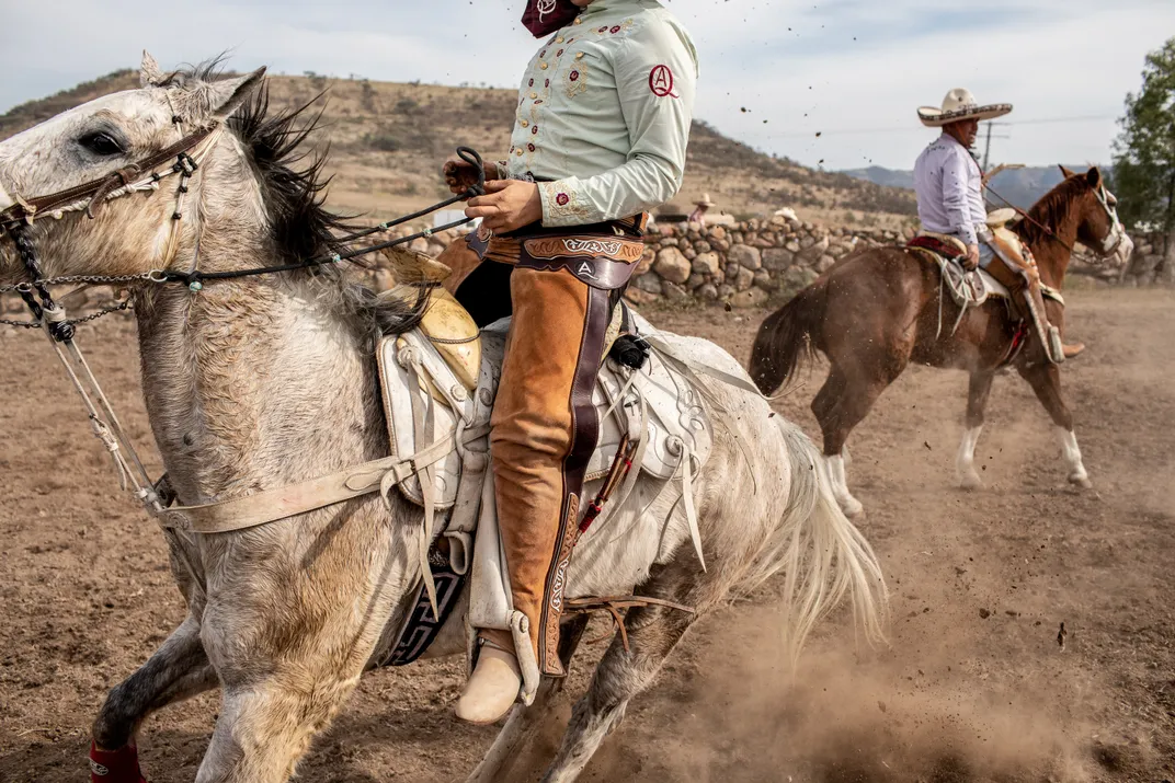 Mexican ranchers with leather chaps, cowboy boots and sombreros ride their horses.