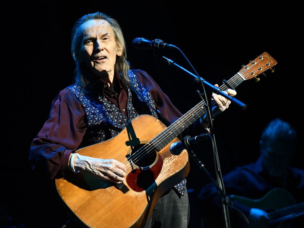 Gordon Lightfoot holds a guitar mid performance