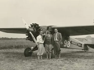 Three-quarter left front view of Cessna BW-5 (r/n C6623, National Air Races race no. 98) on the ground, possibly at Roosevelt Field, Long Island, New York, circa September 1928. Posed standing beside nose of aircraft are pilot Francis D. 