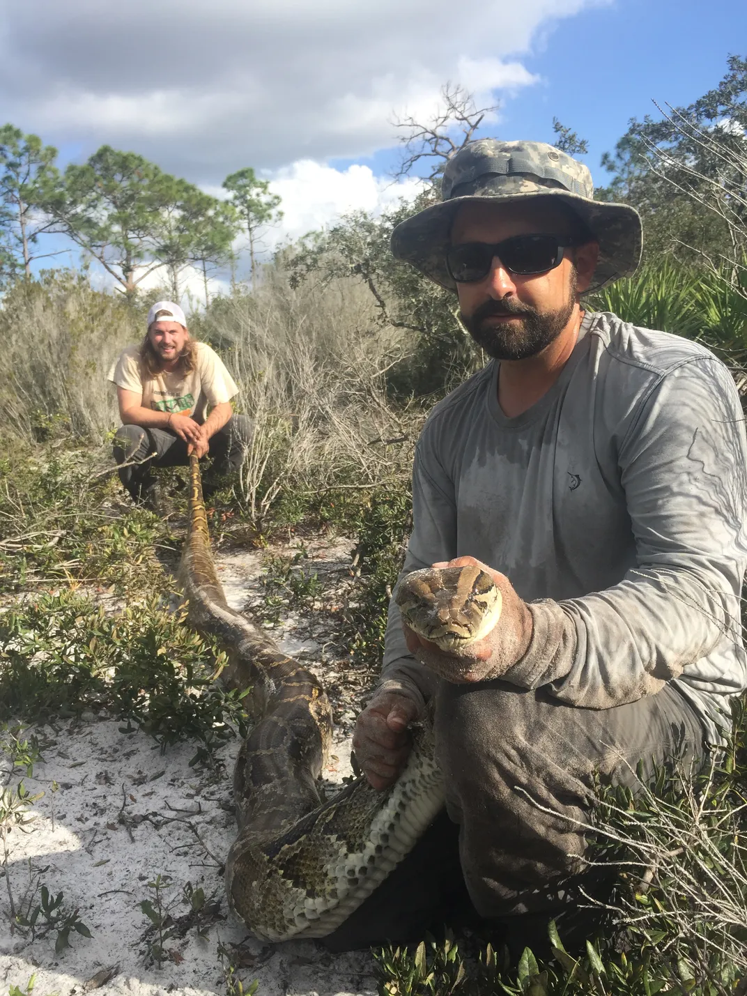Two men with a large snake