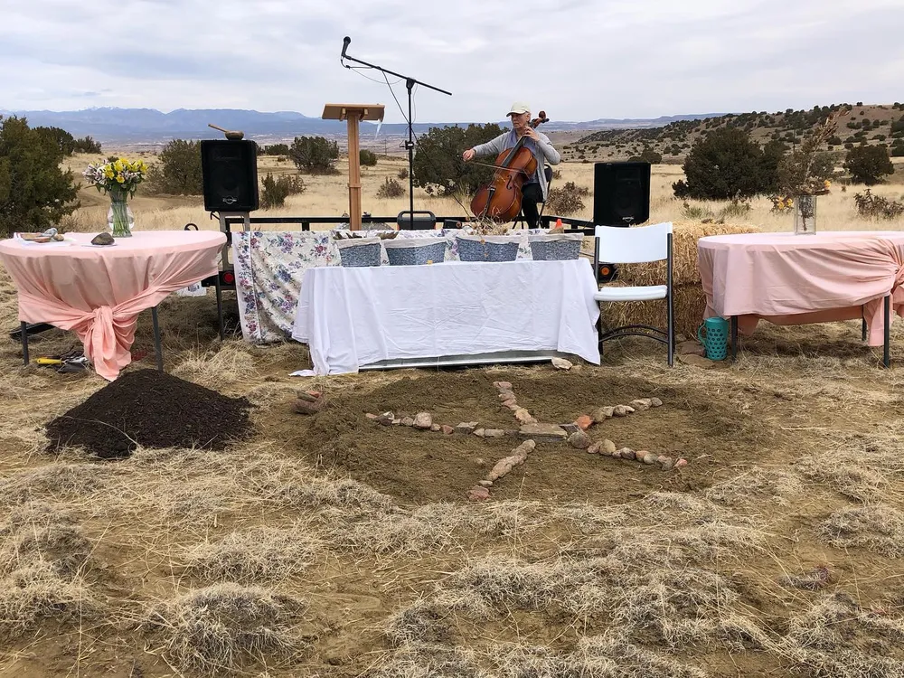Composted human remains with a cello player in the background at a laying out ceremony