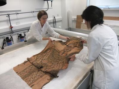 Conservators carefully unfold the shroud, which had been stored in a brown paper parcel for some 80 years. 