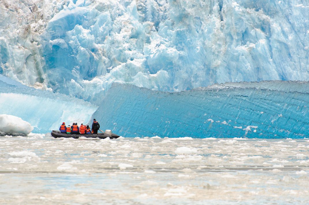 Travelers exploring the edge of a glacier by Zodiac