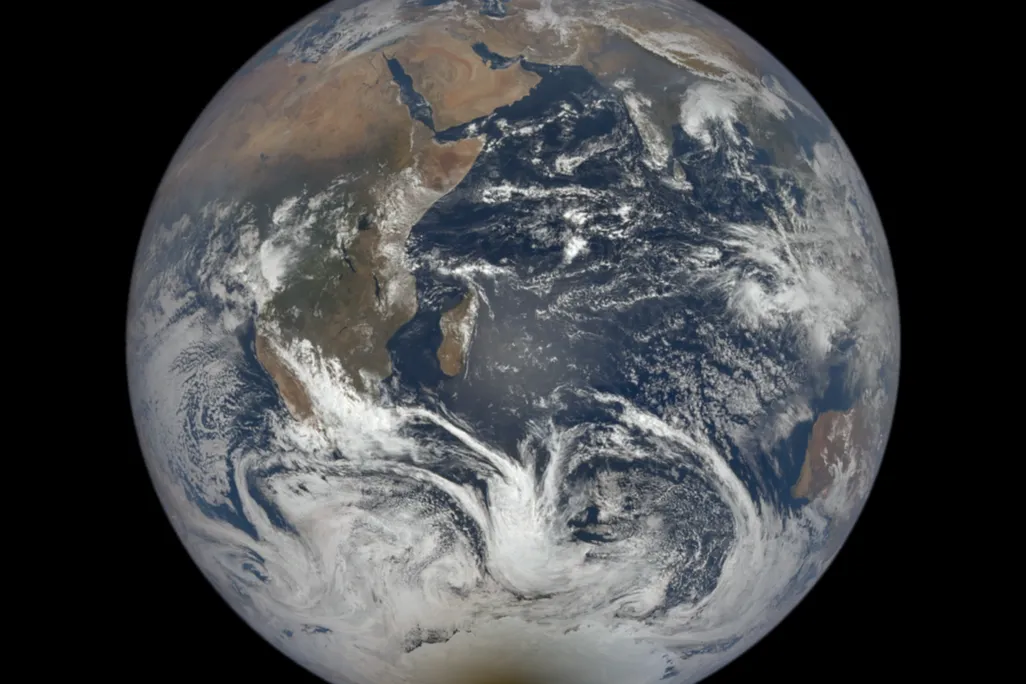 An image of Earth taken from outer space. It shows the whole planet with a dark spot over Antarctica.