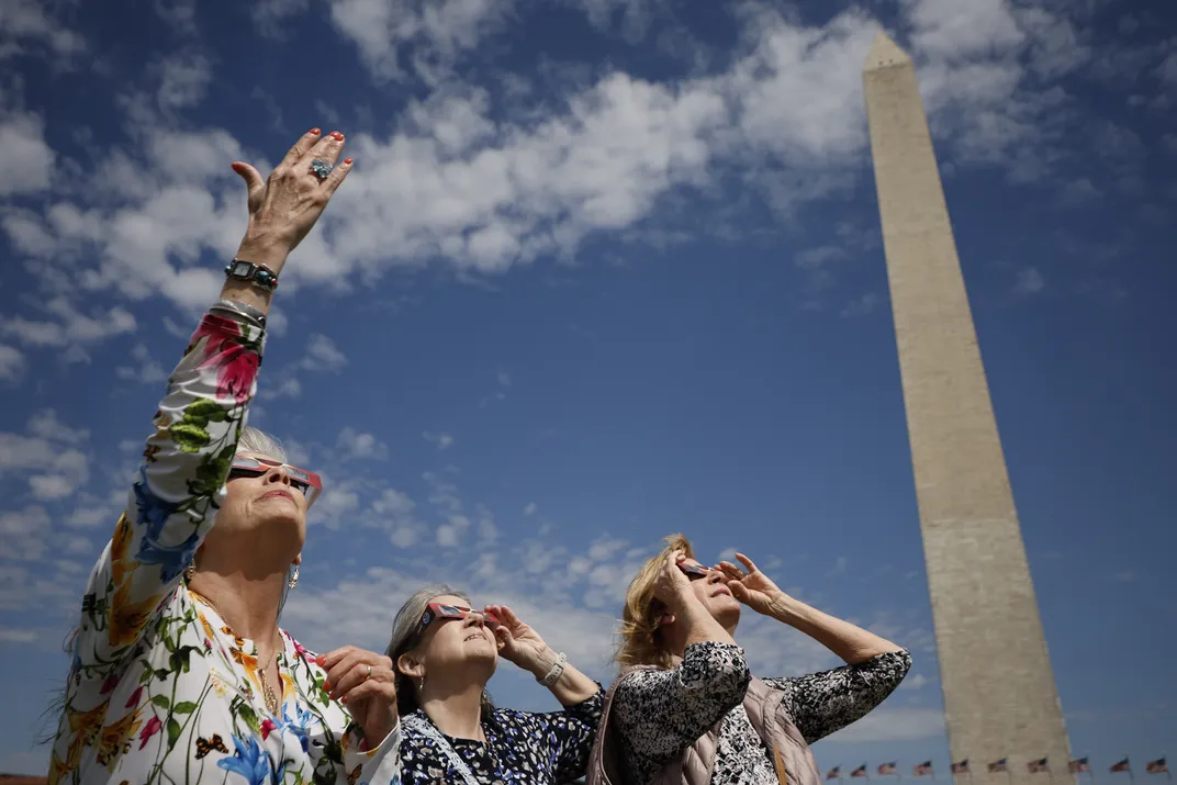 women watch the eclipse in front of the Washington Monument