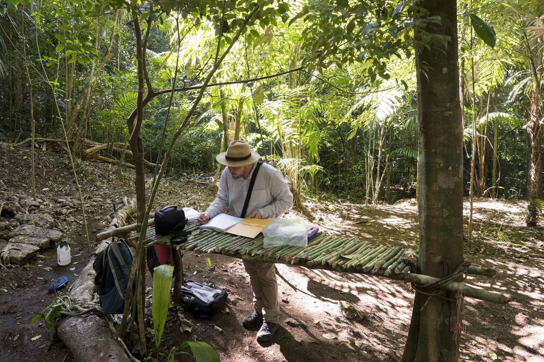 The couple’s son Adrian Chase takes notes on a makeshift table. His research focuses on urban life in Maya civilization.