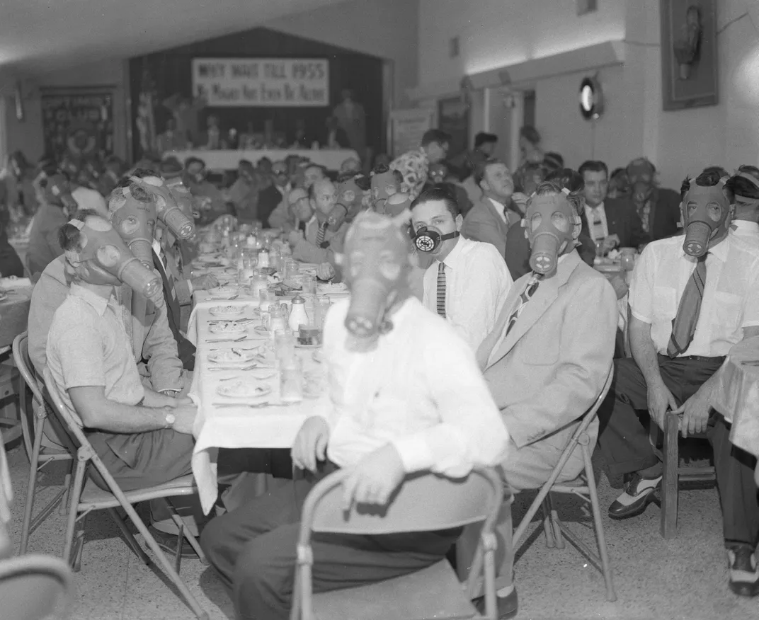 The Highland Park Optimist Club in Los Angeles wearing gas masks at a banquet in 1954.