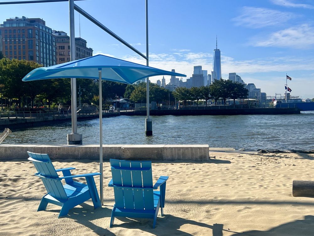 Blue beach chairs on sand with blue umbrella