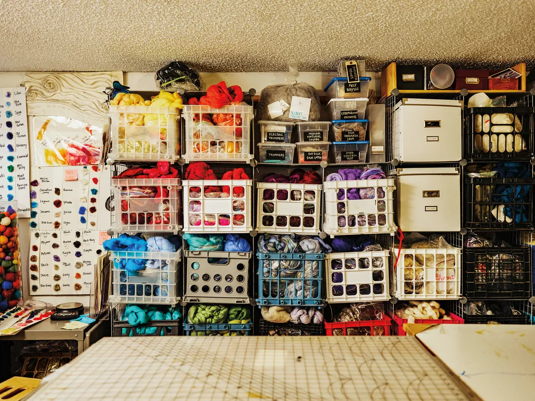 crates full of different color of fabric sit on a shelf