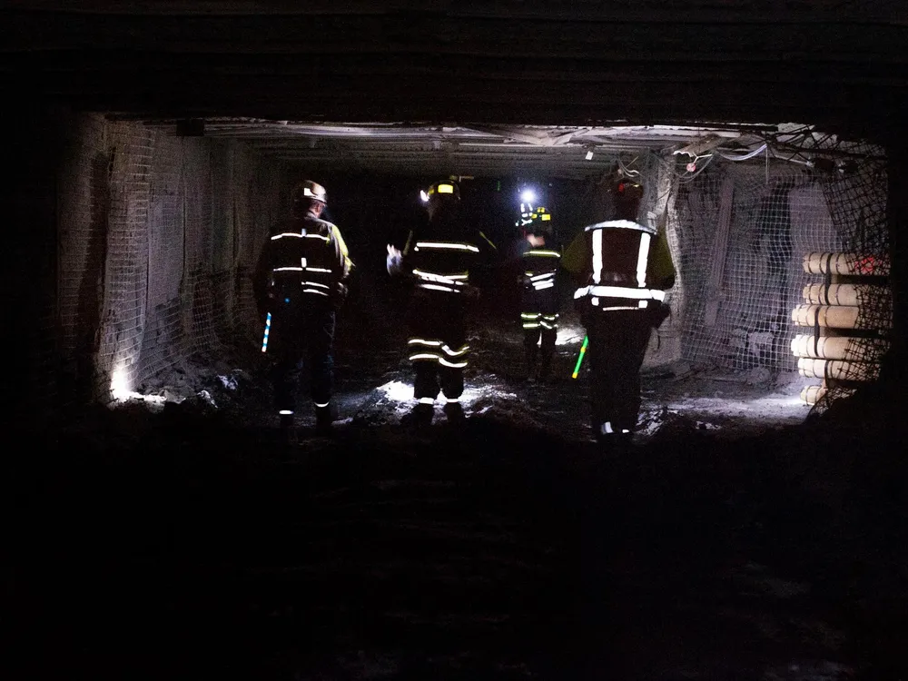 Coal miners dramatically walk through a tunnel