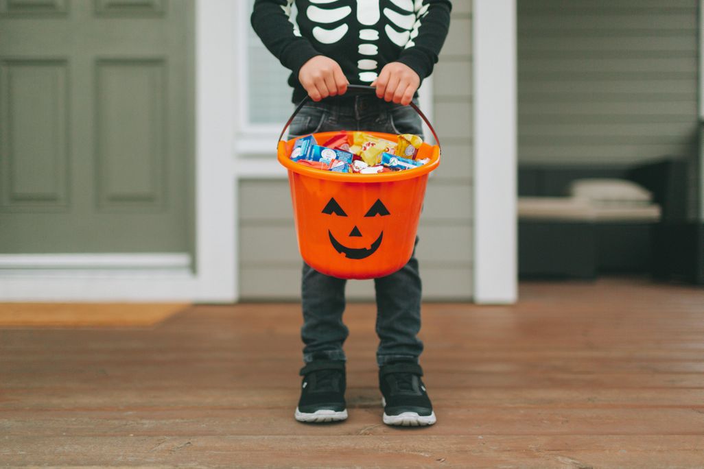 A child wearing a skeleton costume for Halloween holds candy 