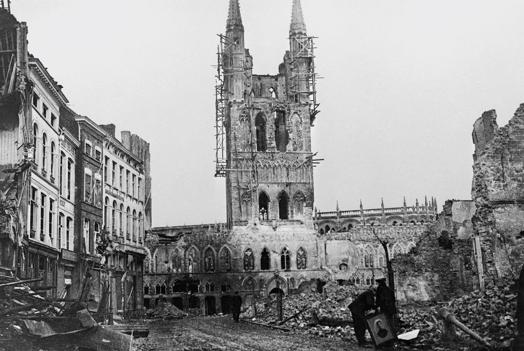 In Ypres, Belgium, residents of the Flemish city retrieve valuables from ruined homes. At center, the Cloth Hall, a medieval marketplace, destroyed by German artillery fire.