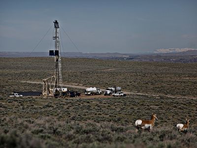 Antelope graze nearby as an oil well is drilled in the Devon Energy oil fields.