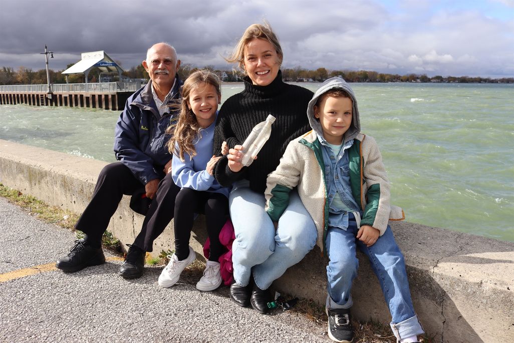 A man, two children and a woman sitting next to a body of water