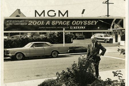 Arthur C. Clarke poses for a photo beneath a sign advertising the motion picture 