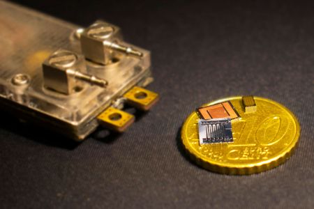 Picture of the top and bottom sides of the chips with integrated microfluidic cooling, next to the miniaturized power converter