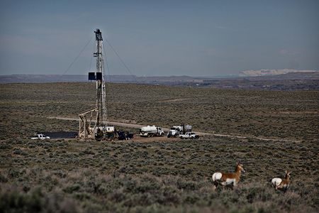 Antelope graze nearby as an oil well is drilled in the Devon Energy oil fields.