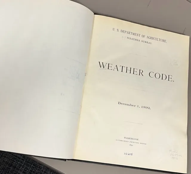 a book open to its title page, which says US Department of Agriculture, US weather bureau, Weather Code, December 1, 1892