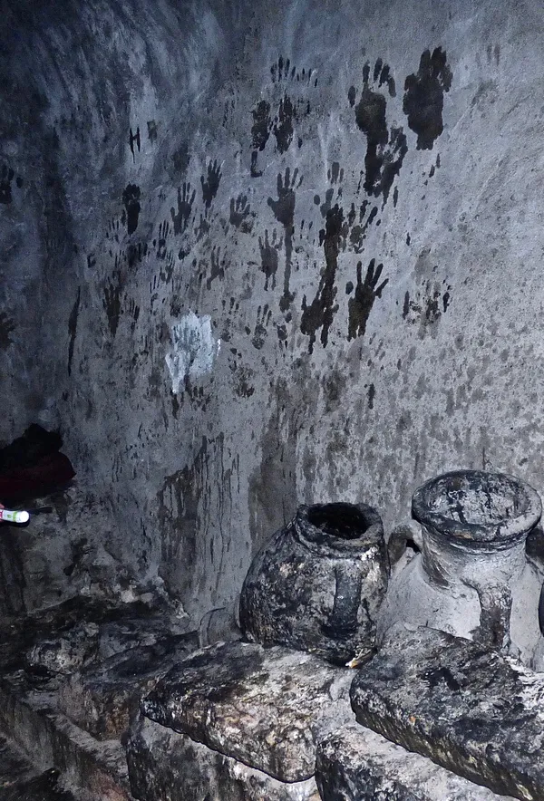 Flashlight illuminated hand and foot print markings on wall in the darkness of Lalish Temple thumbnail