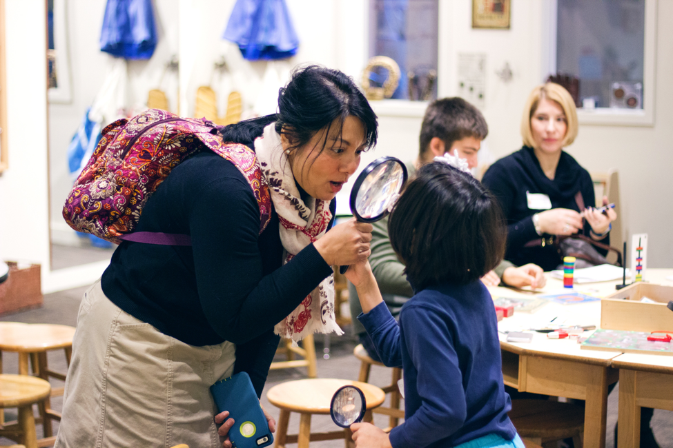 A mother and child look at each other through a magnifying glass.