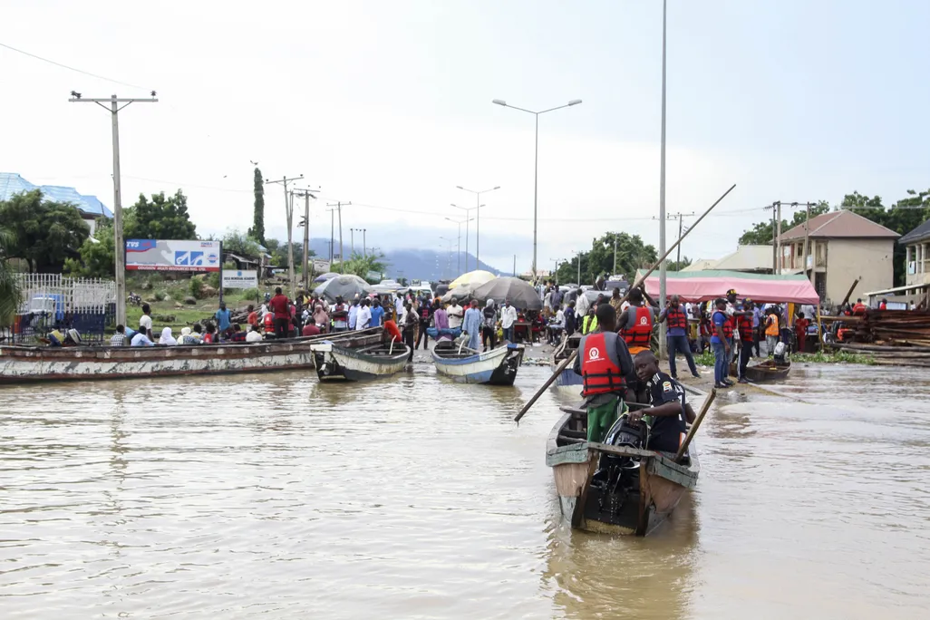 people ride boats through water-covered streets
