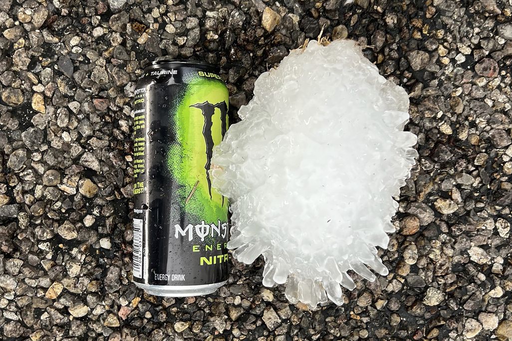 a large hail stone on the ground next to a monster energy can; it is taller than the can