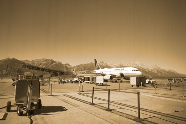 An airplane at Jackson Hole Airport.  Grand Teton mountains in the background. thumbnail