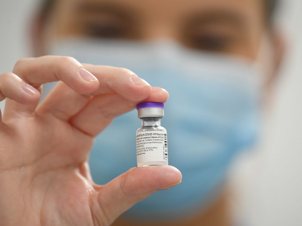 a doctor holds a vial of the Pfizer covid vaccine toward the camera