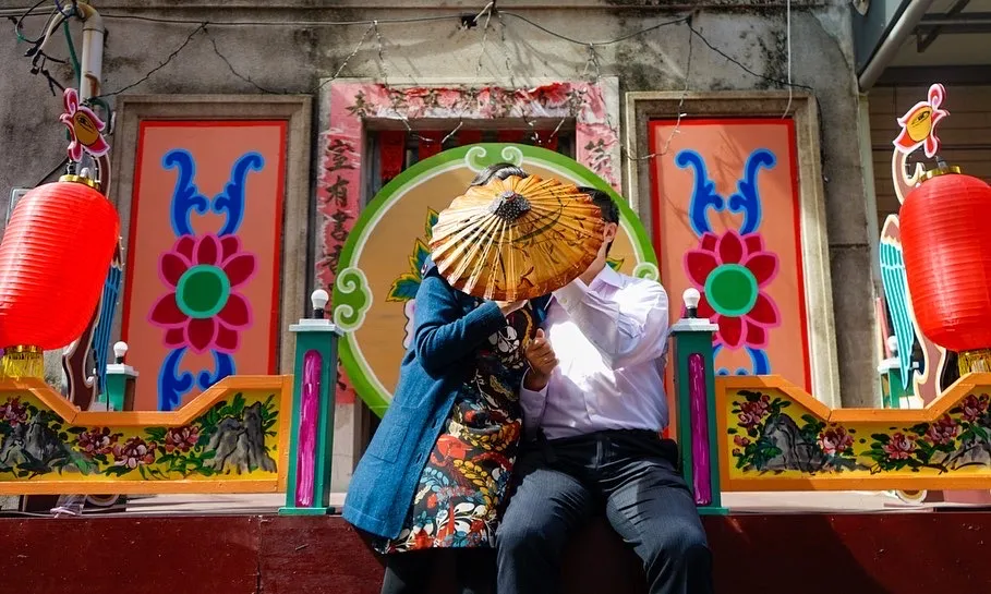 A couple carefully unfolds an oil-paper umbrella, symbolizing the subtle beauty of Chinese culture. It evokes the charm of traditions that are both hidden and revealed.
