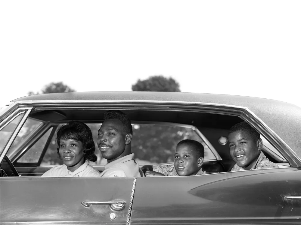 1960s family sitting in four-door sedan automobile